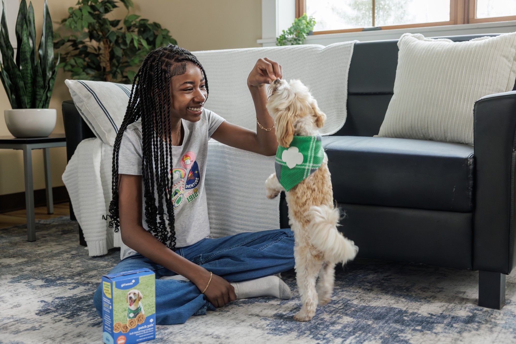 A Girl Scout giving her cream cavapoo a Patch Pals treat at home